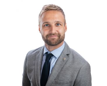 Man smiling wearing a suit in front of a white background as part of a Headshot Photography Shoot.