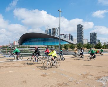 People on bikes riding together over a bridge as part of an organised event.