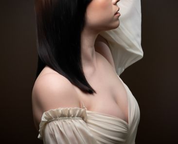 Profile view of young lady with her hand wrapped around her head. Product photography.