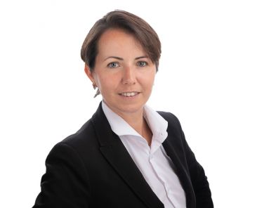 Woman in suit in front of a white background as part of a headshot photography shoot.